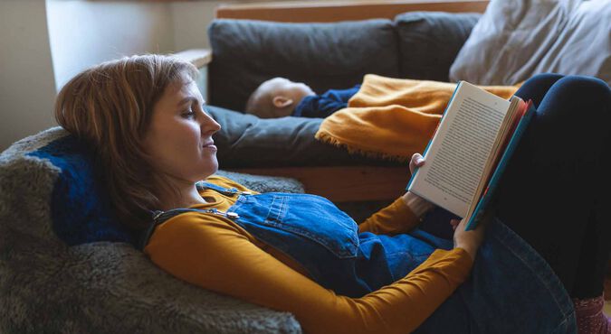 Mãe lendo livro ao lado de seu bebê