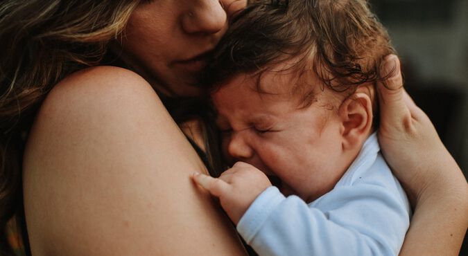 Mãe sorrindo enquanto abraça seu bebê recém-nascido