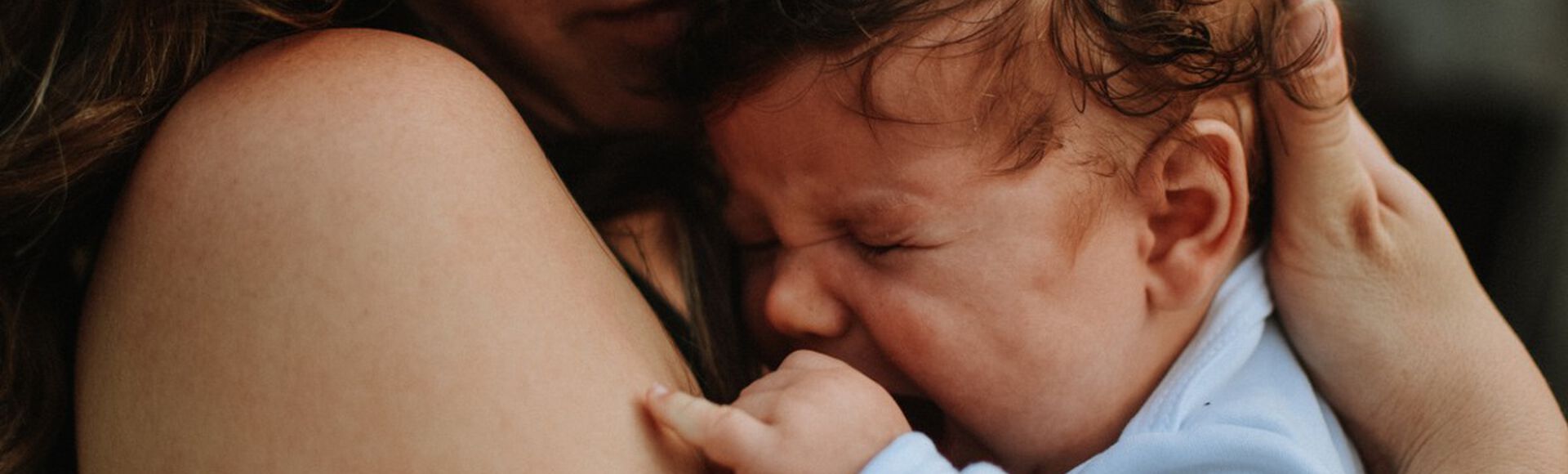 Bebê chorando no colo da mãe e sendo amparado