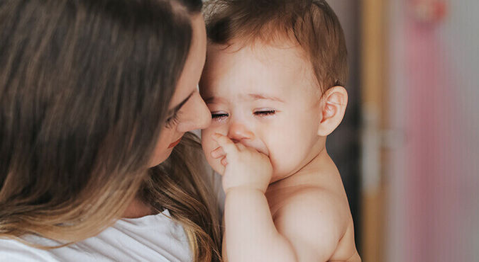 Bebê chorando no colo da mãe