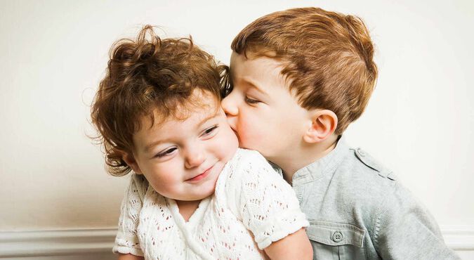 Irmão dando beijo na bochecha do irmão mais novo