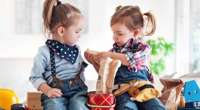 Duas meninas sentadas dividindo um lanche