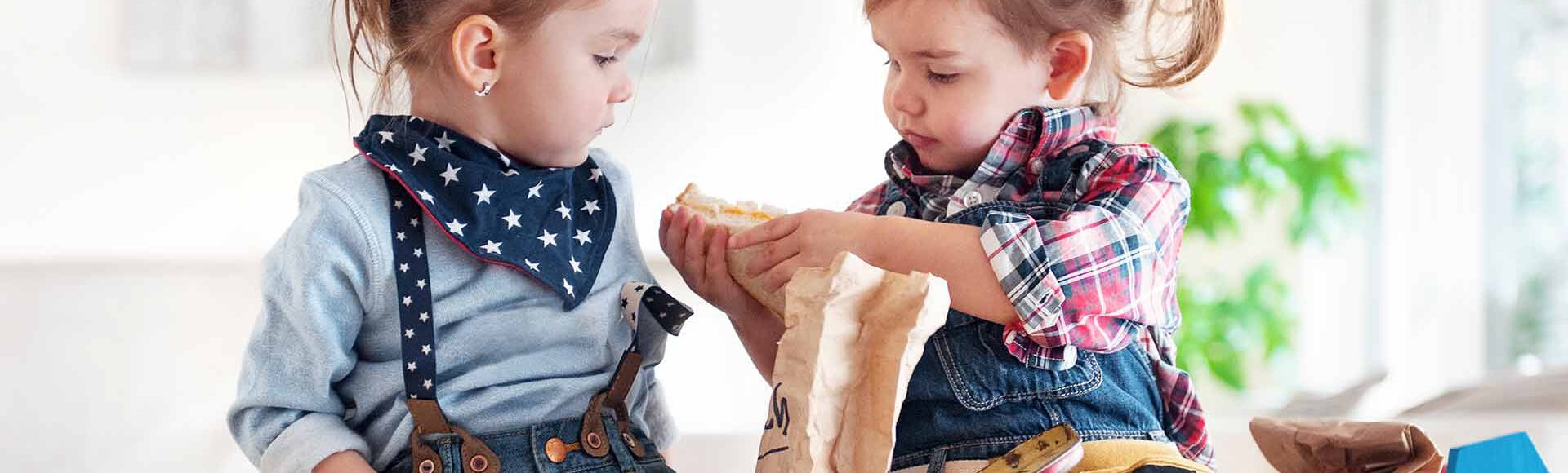 Duas meninas sentadas dividindo um lanche