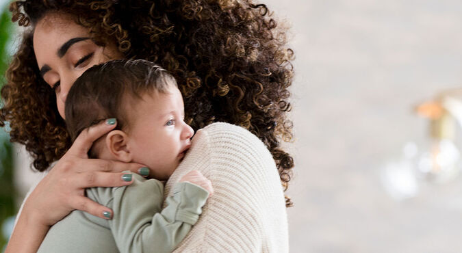 Bebê com cólica no colo da mãe