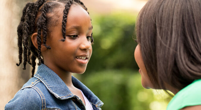 Mãe abaixada conversando com a filha