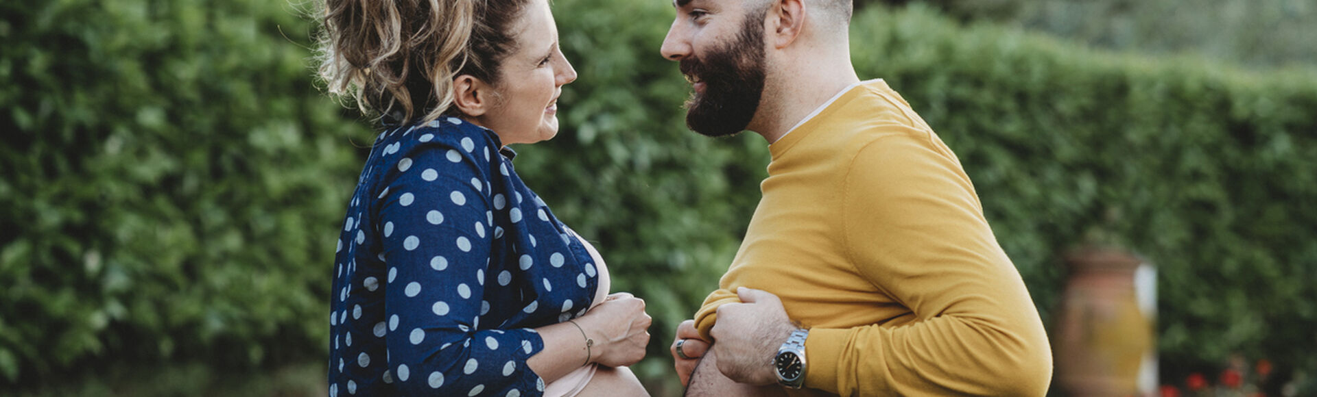 Um mulher gestante de frente para o seu companheiro com a barriga encostada na barriga dele, mostrando como é a síndrome de couvade