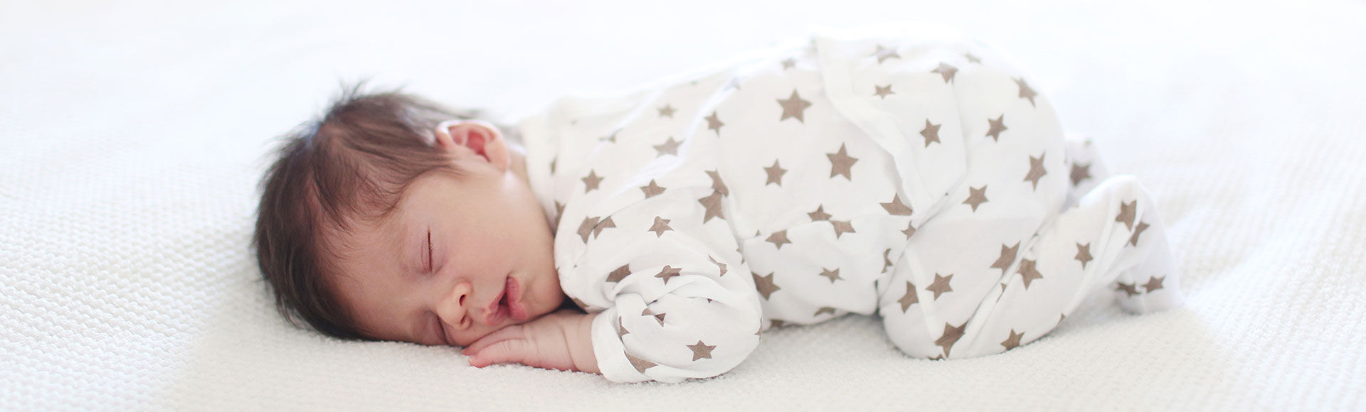 Bebê dormindo de bruços em colchão branco