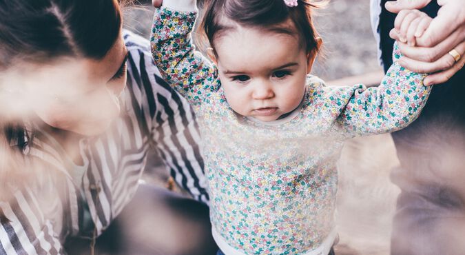 Bebê caminhando de mãos dadas com papai e mamãe