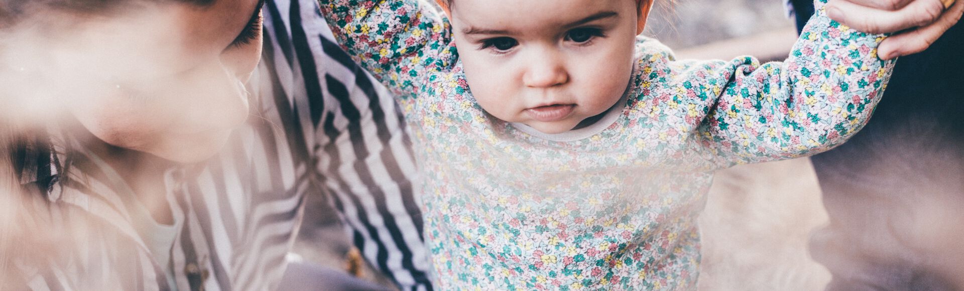 Bebê caminhando de mãos dadas com papai e mamãe