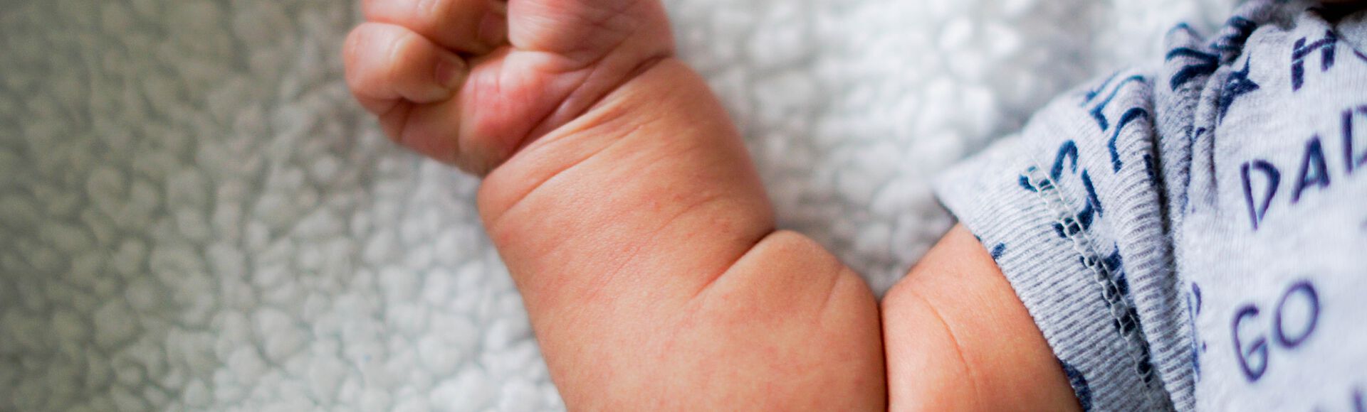 Bebê deitado na cama com os braços abertos