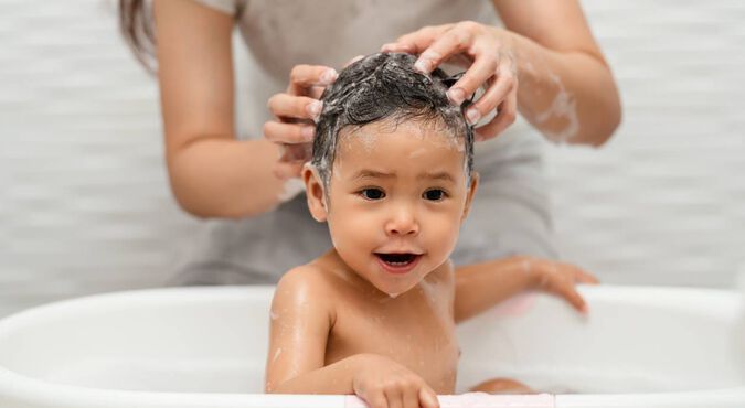 Criança lavando o cabelo com shampoo e condicionador infantil