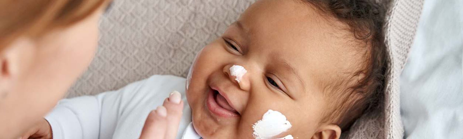 Bebê sorrindo enquanto recebe cuidados na pele.