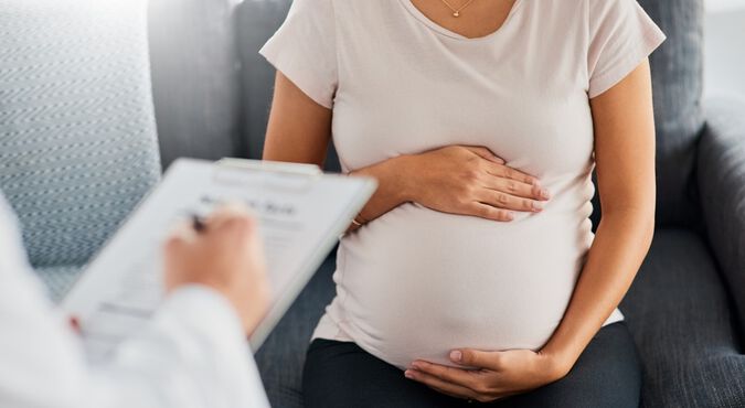 Gestante com as mãos na barriga durante consulta médica