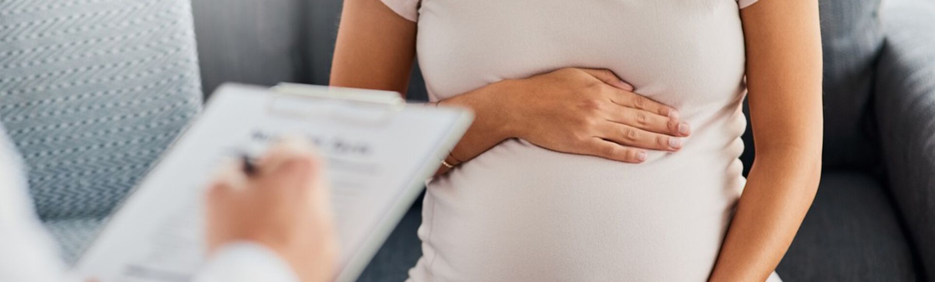 Gestante com as mãos na barriga durante consulta médica