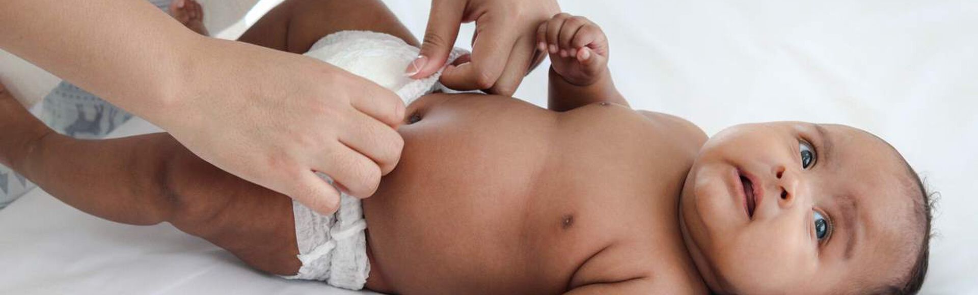 Bebê deitado enquanto tem a fralda trocada por um adulto