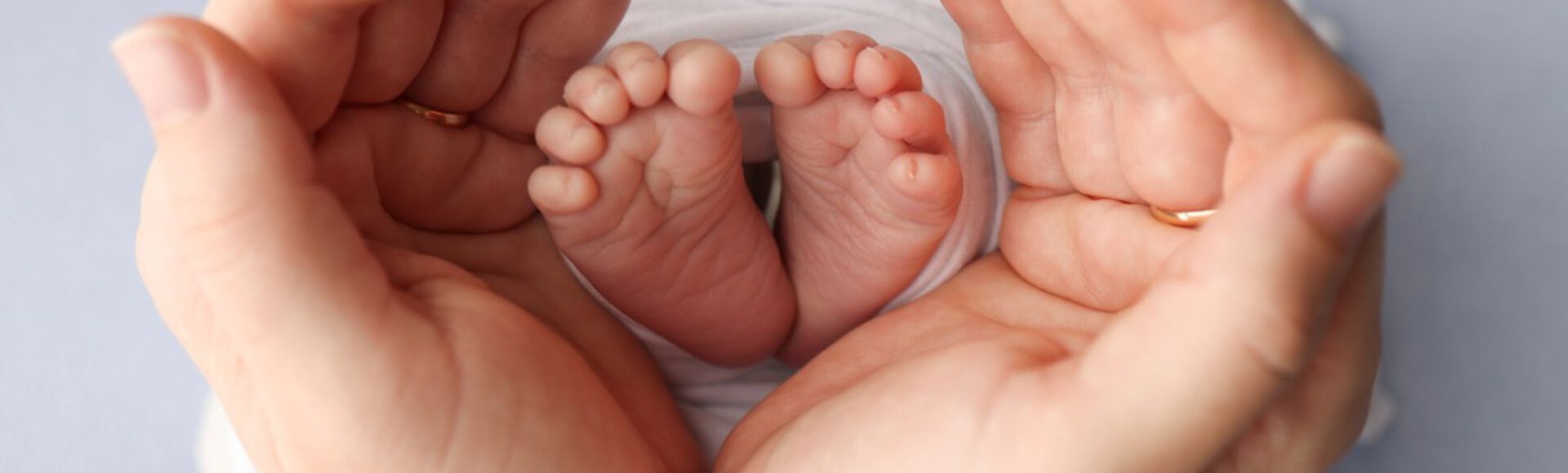 Pés de bebê envoltos em mãos de adulto