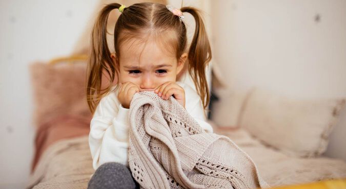 Menina chorando e segurando cobertor