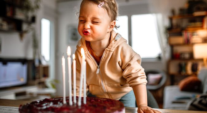 Criança pequena soprando velas em bolo de aniversário