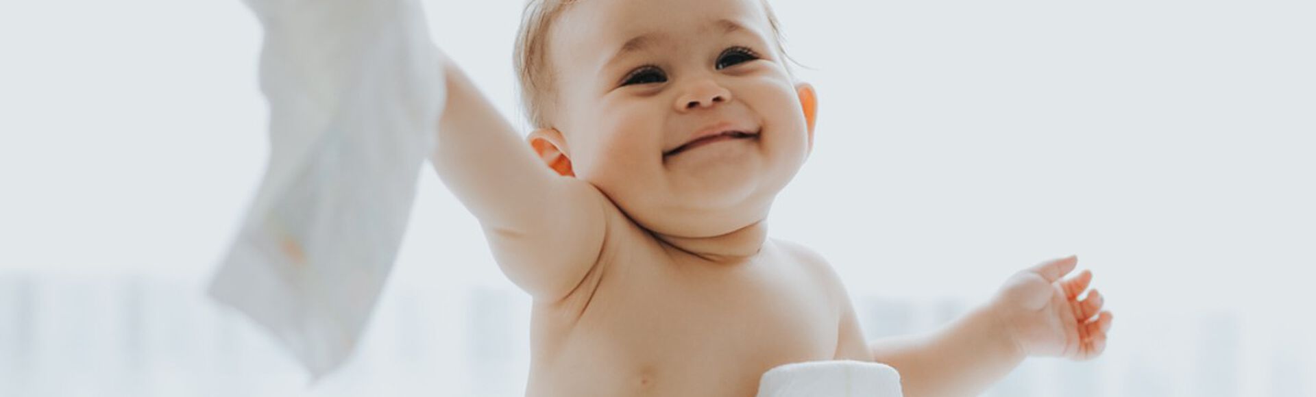 Bebê  sorridente sentado junto a pilha de fraldas