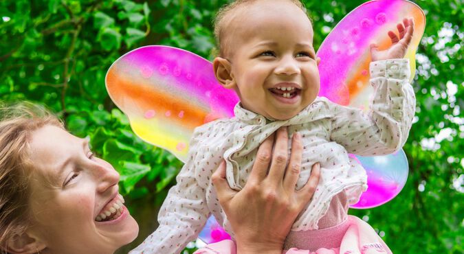 Mãe levantando a filha fantasiada em momento de curtição no carnaval