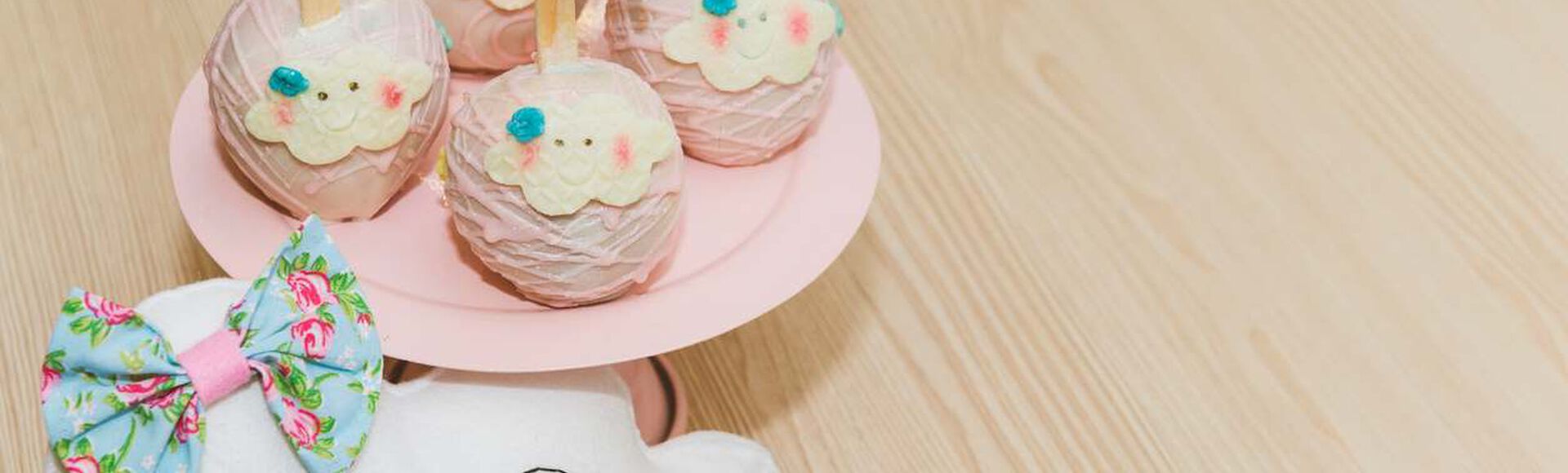 Centro de mesa com maçãs do amor confitadas com chocolate rosa, com tema de nuvenzinha. Ao lado, uma nuvem de pelúcia com lacinho.