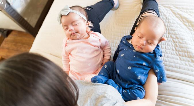 Mãe com dois bebês gêmeos dormindo em seu colo