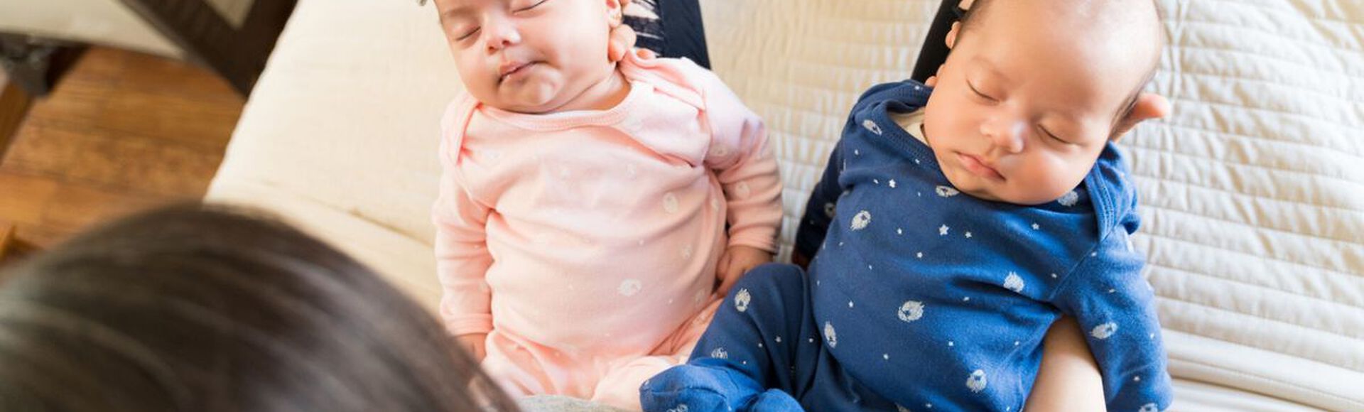Mãe com dois bebês gêmeos dormindo em seu colo