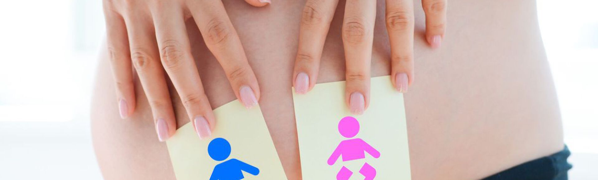 Gestante com imagens de desenhos de bebes, um rosa e um azul, em frente à barriga