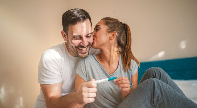 Casal feliz segurando teste de gravidez