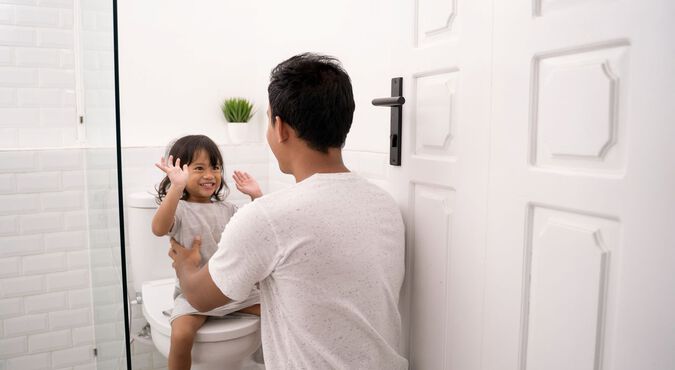 Pai ensina filha a usar o banheiro de forma autônoma.