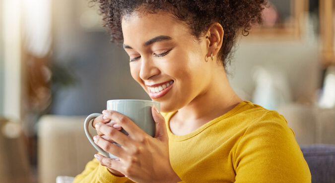 Mulher negra vestindo blusa amarela tomando chá