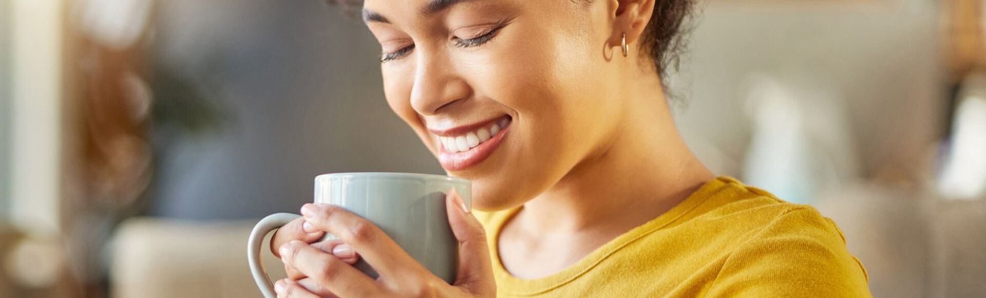 Mulher negra vestindo blusa amarela tomando chá