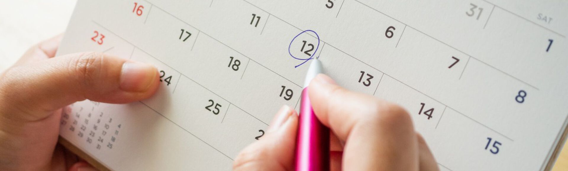 Pessoa segurando folha de calendário e marcando dia