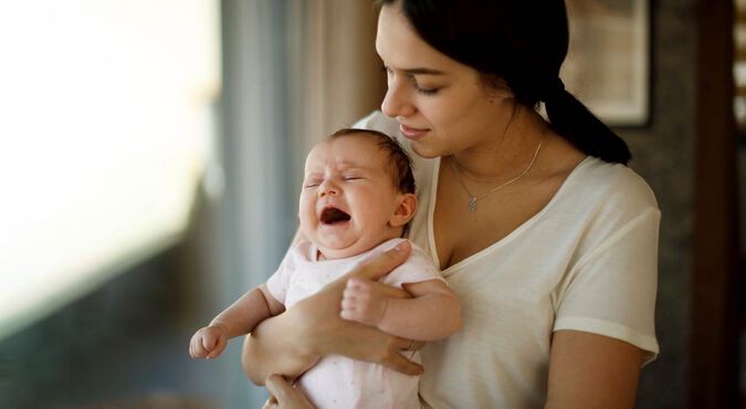 Mãe segurando bebê chorando
