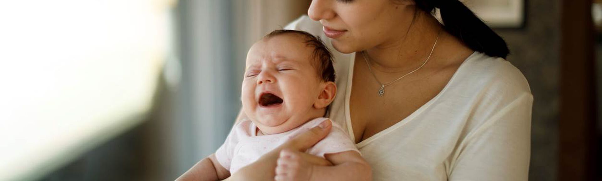 Mãe segurando bebê chorando