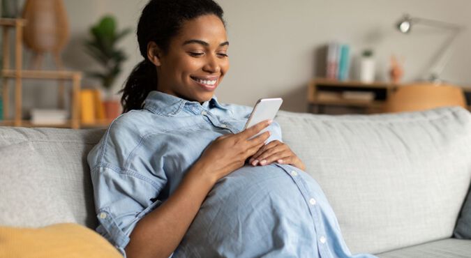 Gestante sentada em sofá olhando celular