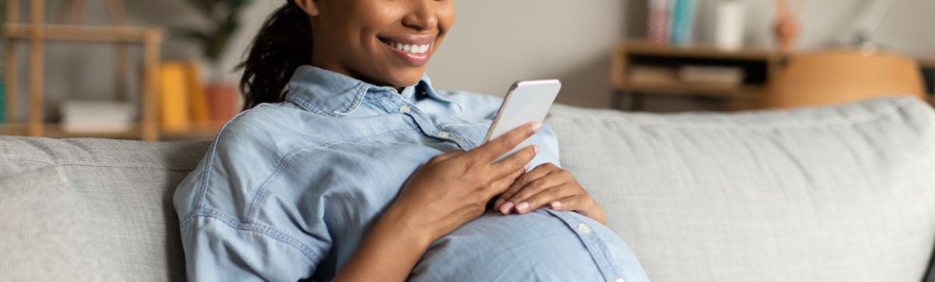 Gestante sentada em sofá olhando celular