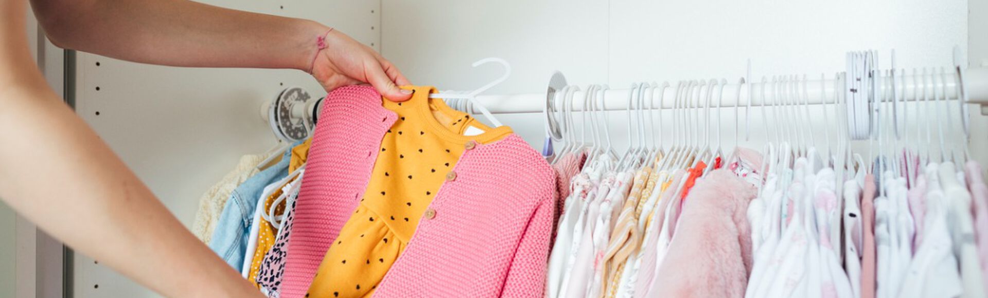Mulher escolhendo roupas infantis em cabideiro