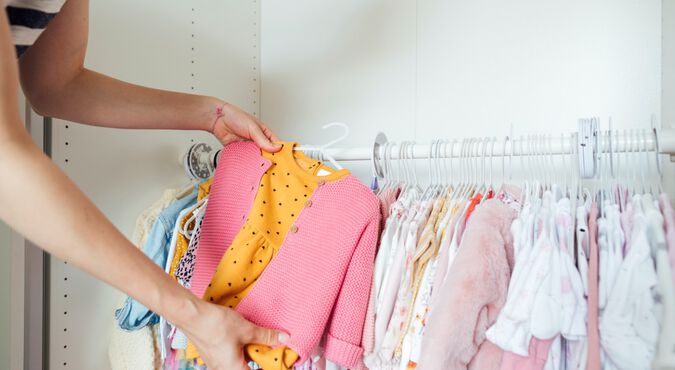 Mulher escolhendo roupas infantis em cabideiro