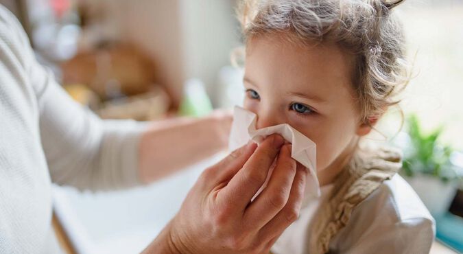Adulto limpando o nariz de uma criança com um lenço de papel