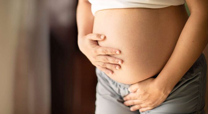 Mulher grávida segurando a barriga com as mãos