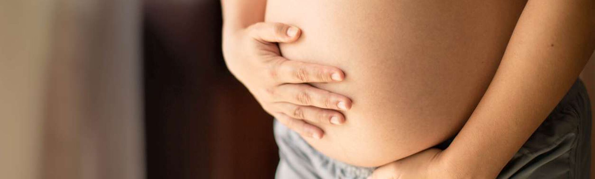 Mulher grávida segurando a barriga com as mãos