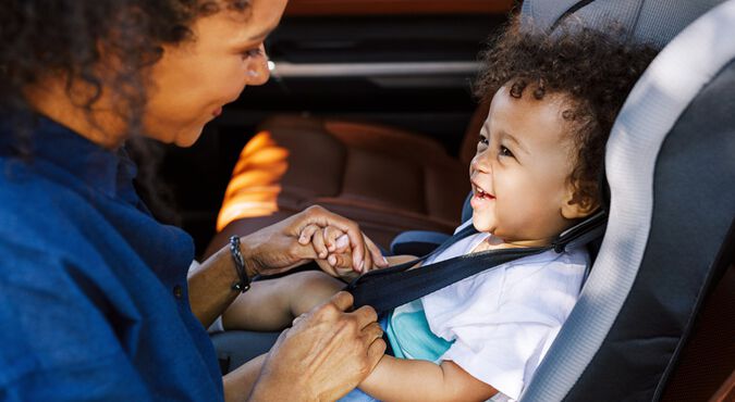 Mãe negra ajustando bebê na cadeirinha no carro