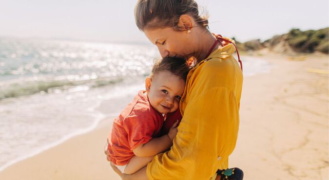 Bebê no colo da mãe na praia