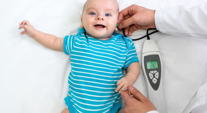 Bebê sorrindo enquanto é examinado por um pediatra.