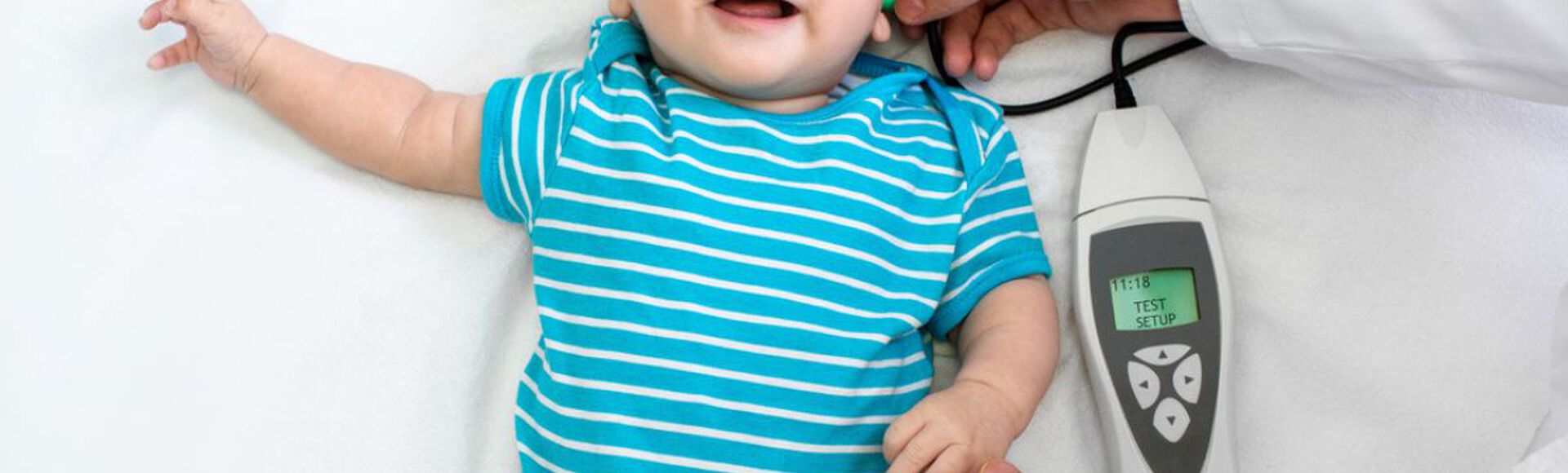 Bebê sorrindo enquanto é examinado por um pediatra.