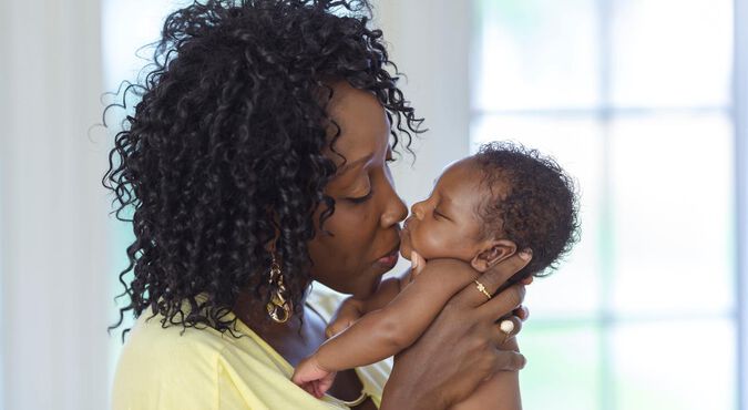 Mãe beijando seu bebê com cabelo cacheado