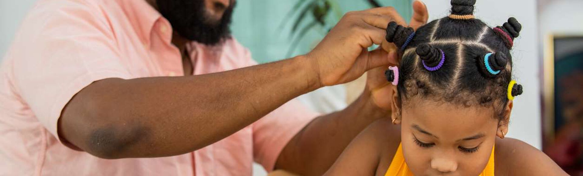 Pai fazendo penteado infantil na filha