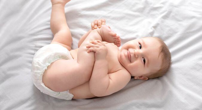 Bebê sorridente sentado junto a pilha de fraldas