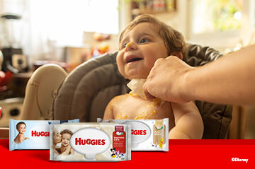 Pai limpando o bebê com lencinhos umedecidos Huggies Supreme Care.